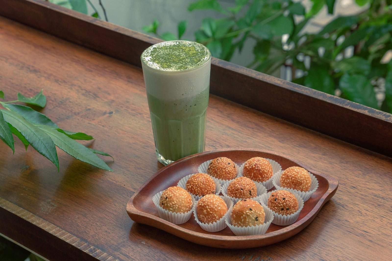 Wooden table with sesame balls and green tea latte in Ho Chi Minh City.